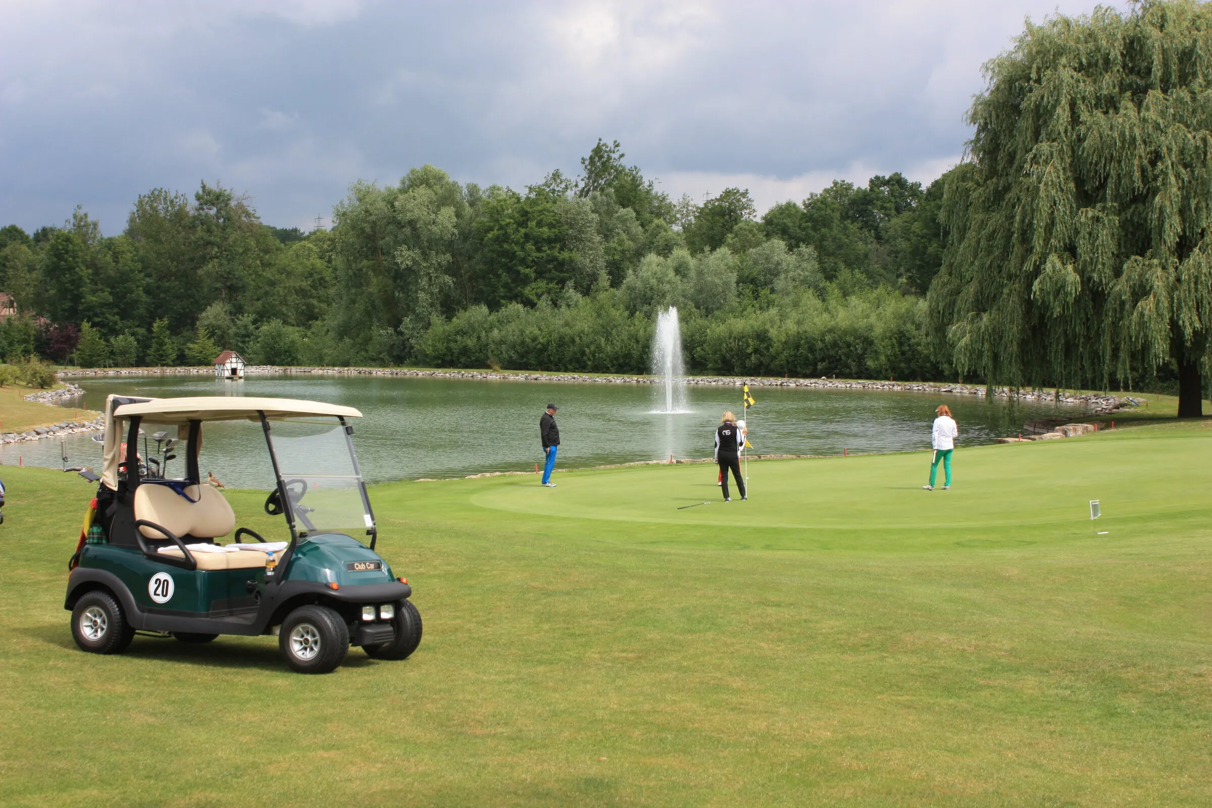 Golfcart am Teich mit Fontäne.