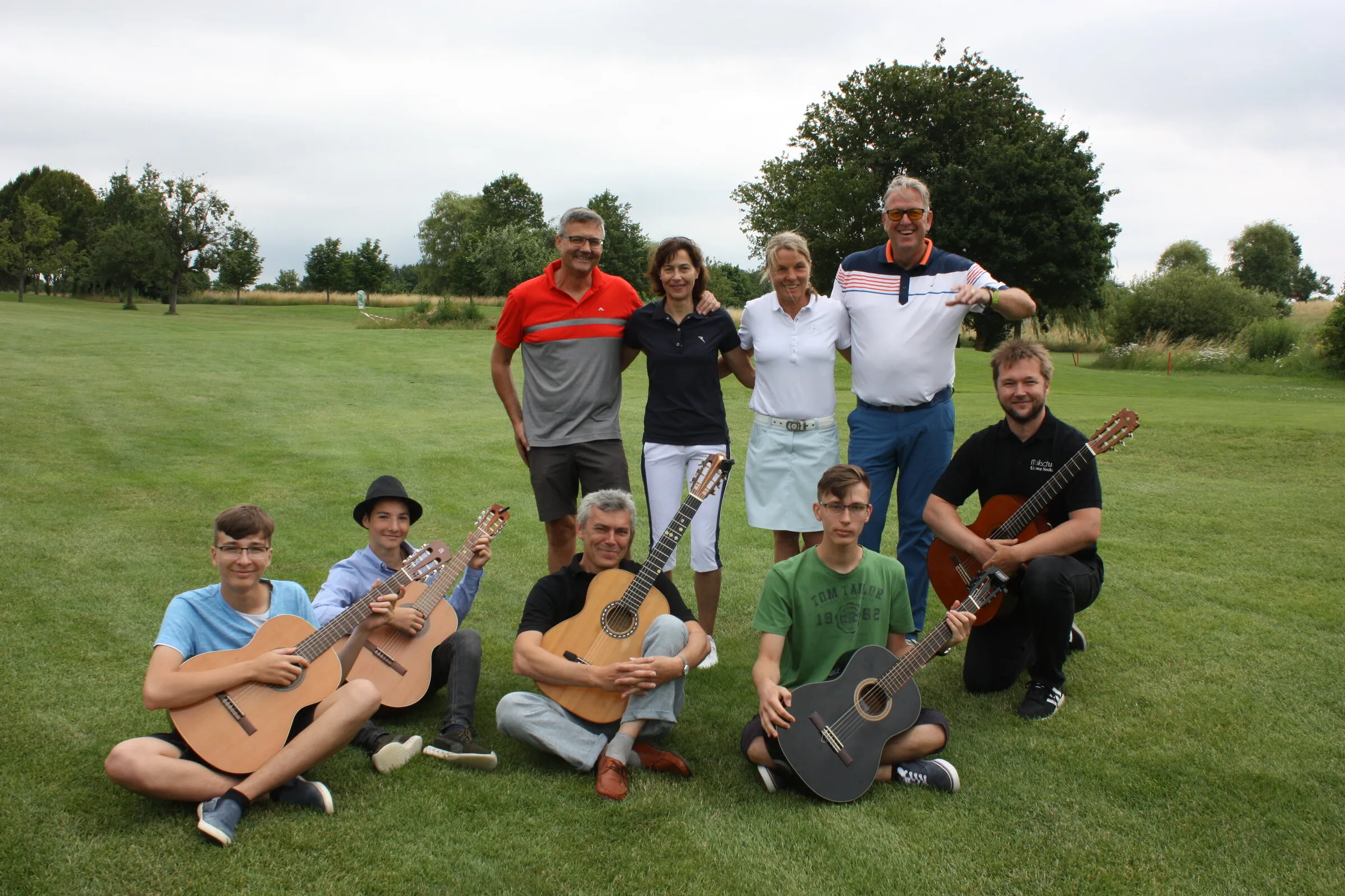 Gitarrenensemble und Golfer gemeinsam auf dem Fairway.