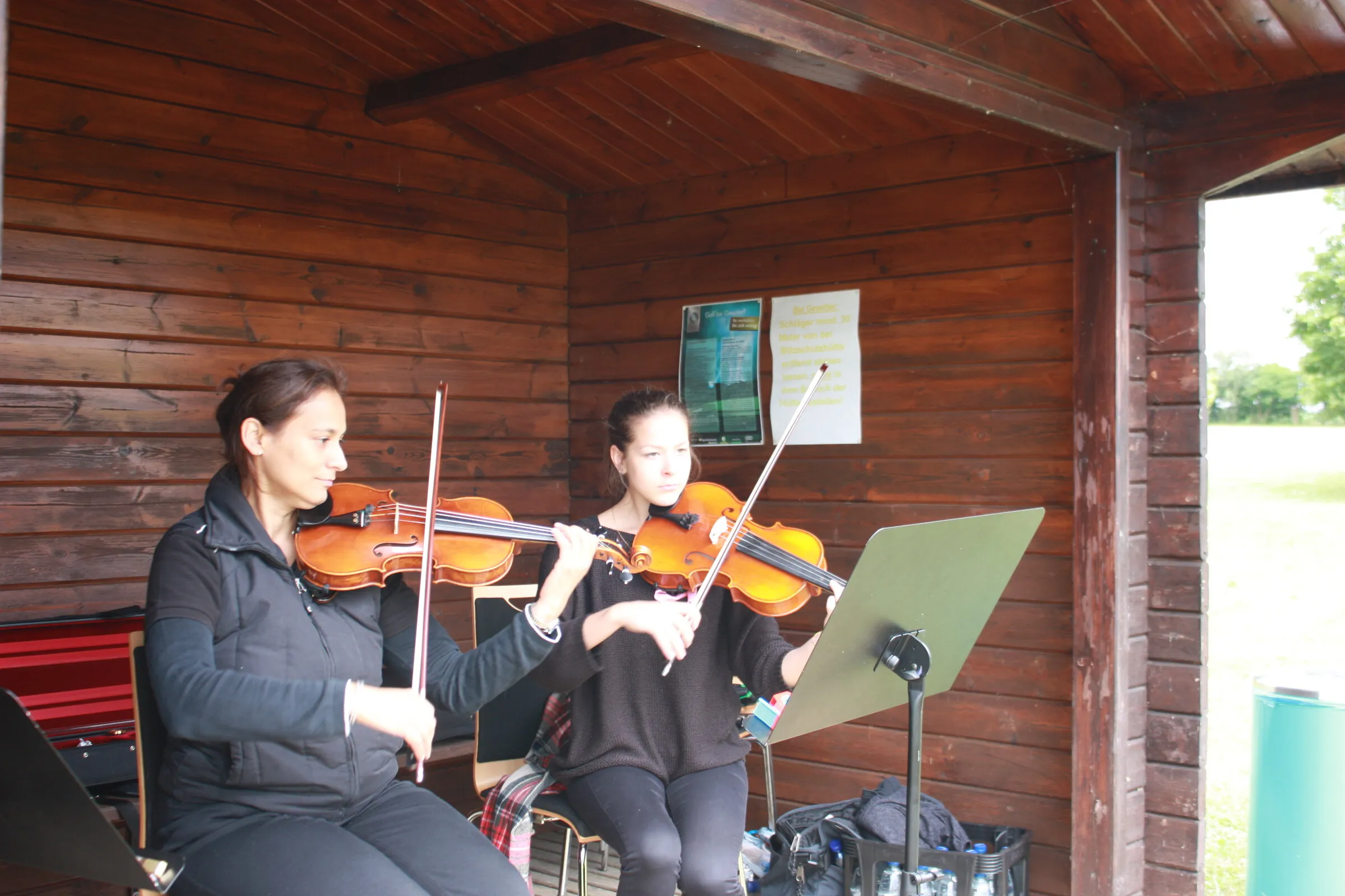 Geigenduo in der Holzhütte am Spielfeldrand.