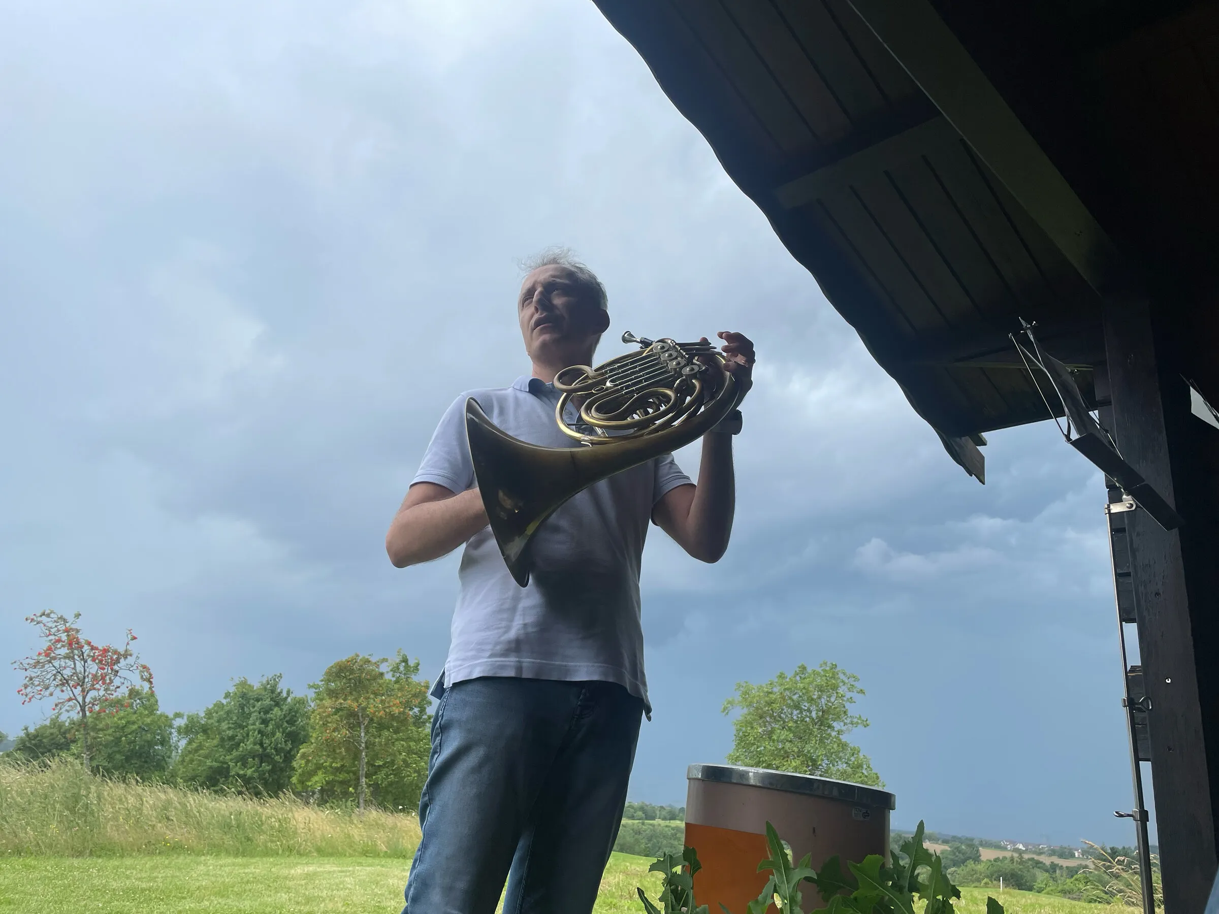 Ein Hornist spielt auf dem Platz unter dunklen Wolken.