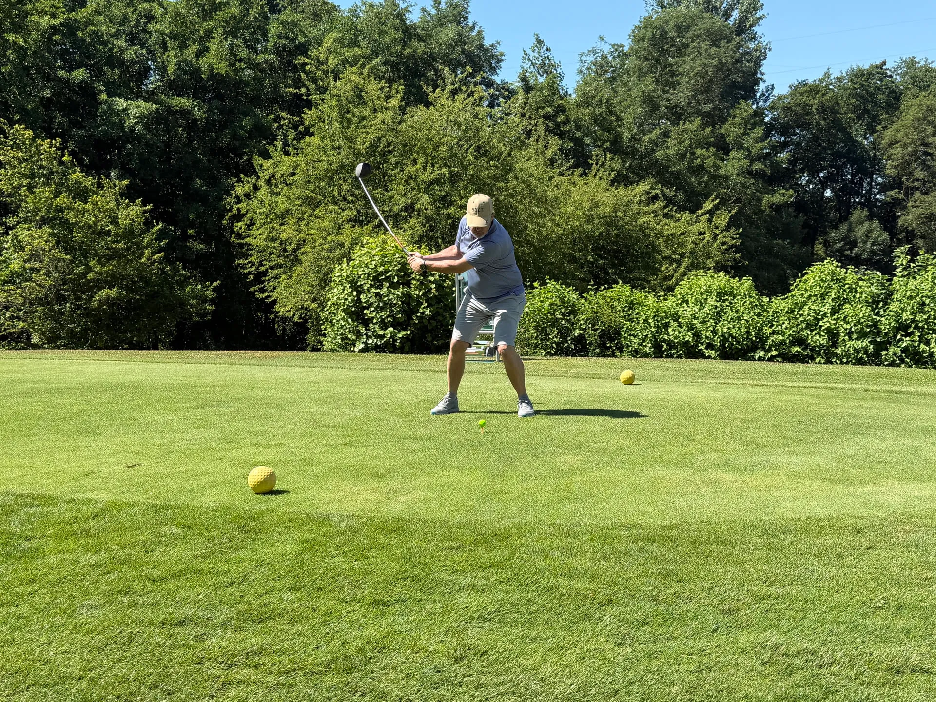 Golfer beim Abschlag neben einem Golfcart