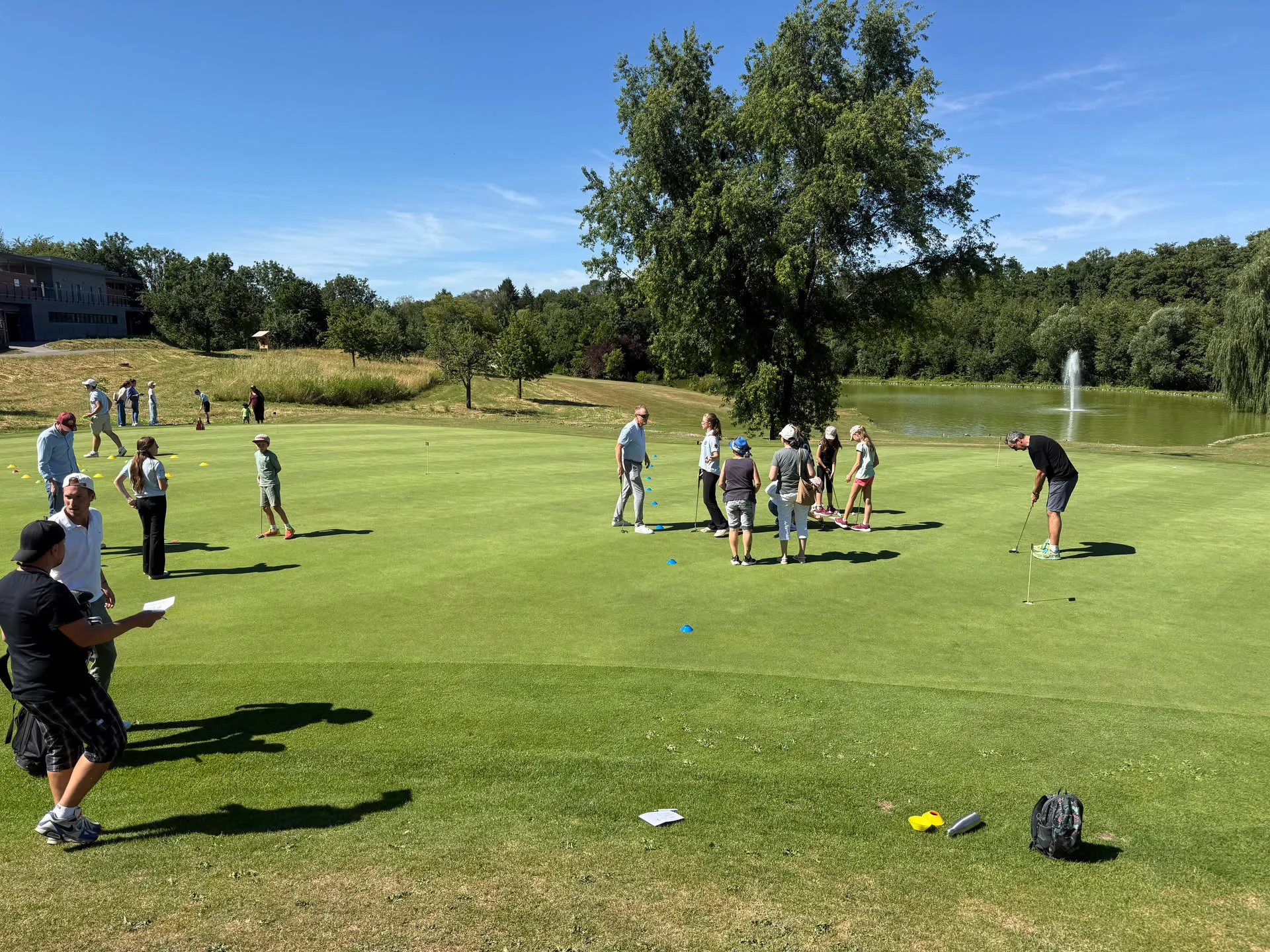 Gäste am Putting-Grün, im Hintergrund der See mit Fontäne